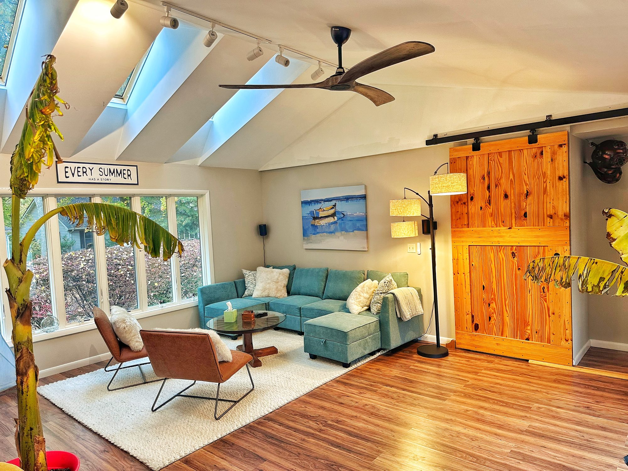 Living room with teal sectional, barn door, and skylights